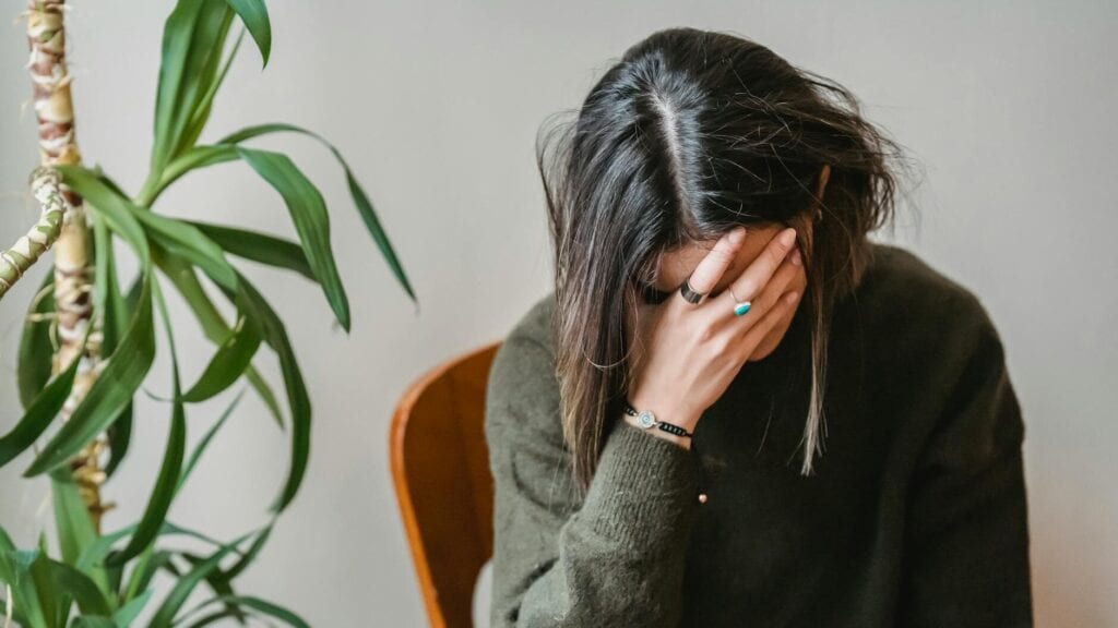 worried young woman covering face with hand