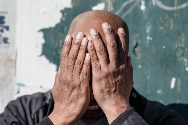 black man covering face with hands